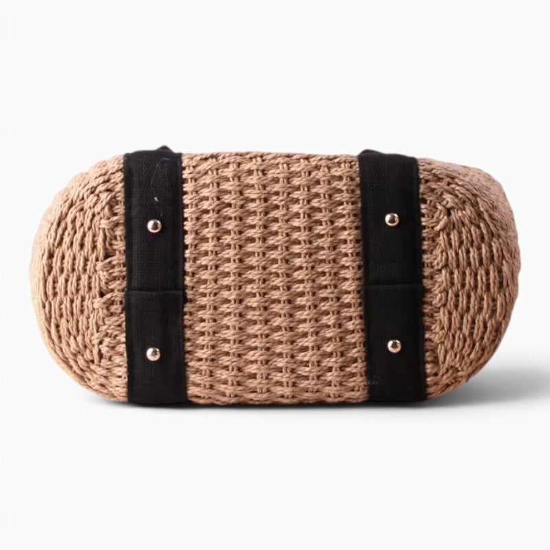 Sac cabas de plage en paille tressée beige avec détails noirs, vue de dessous montrant la structure robuste