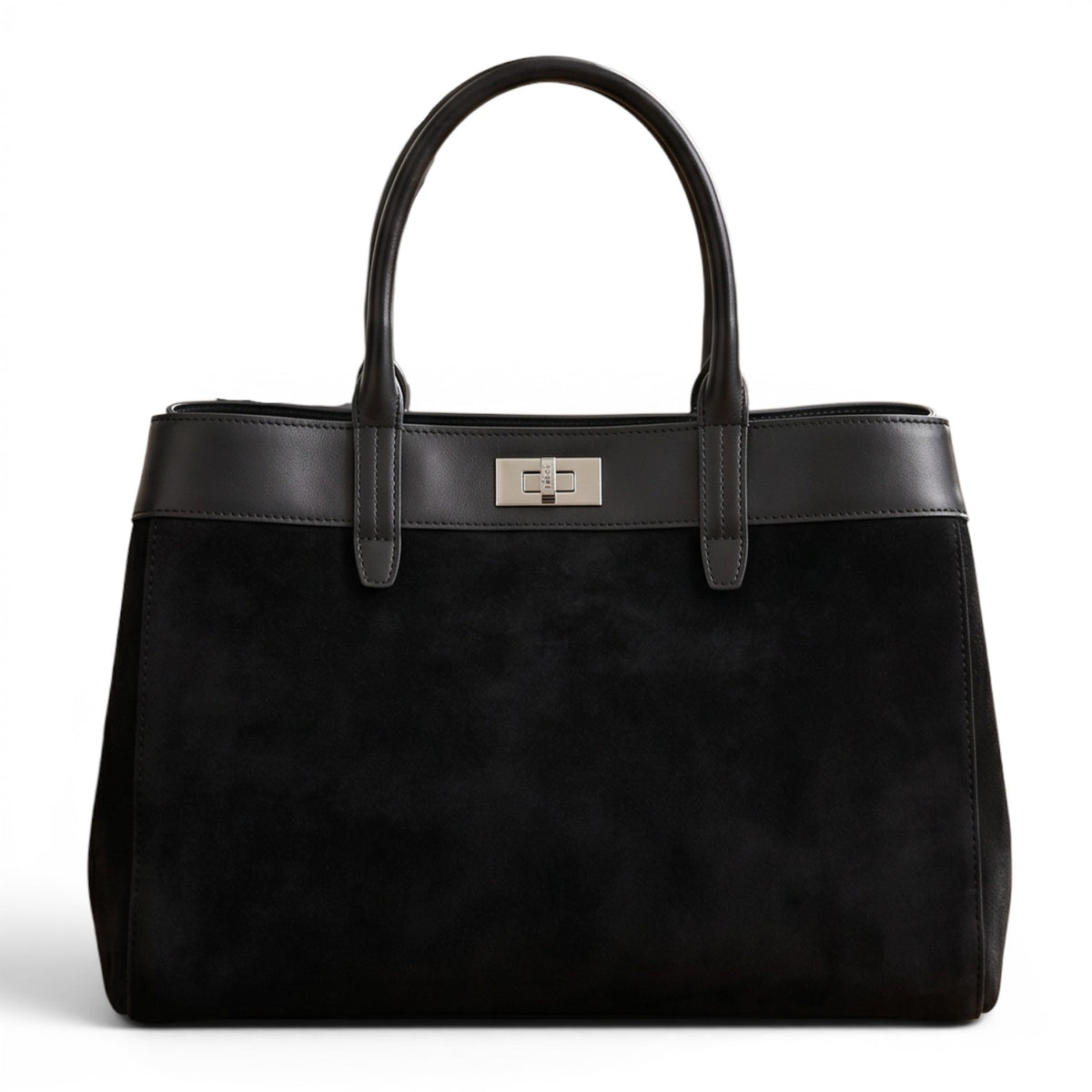 Sac grand cabas noir en cuir suédé et cuir lisse avec fermoir métallique, posé sur un parquet dans un intérieur chic.